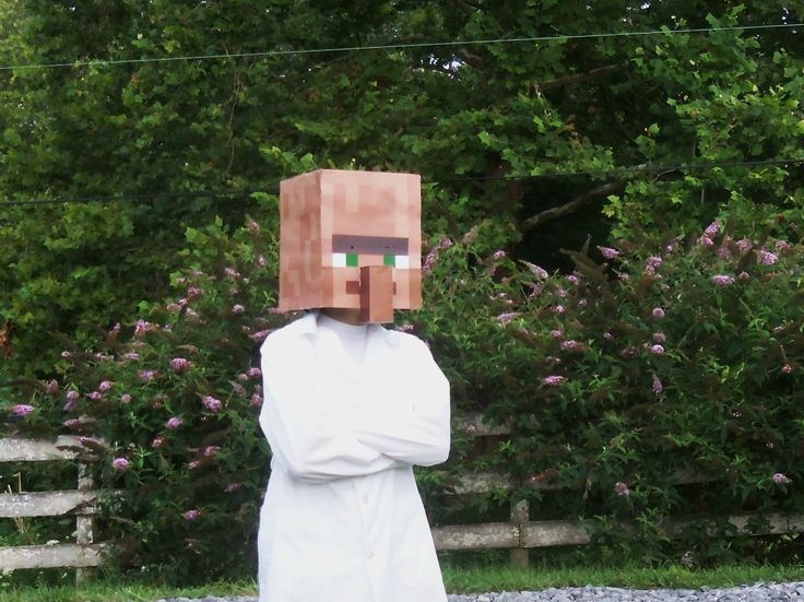 a man wearing a paper bag over his head in front of some bushes and trees