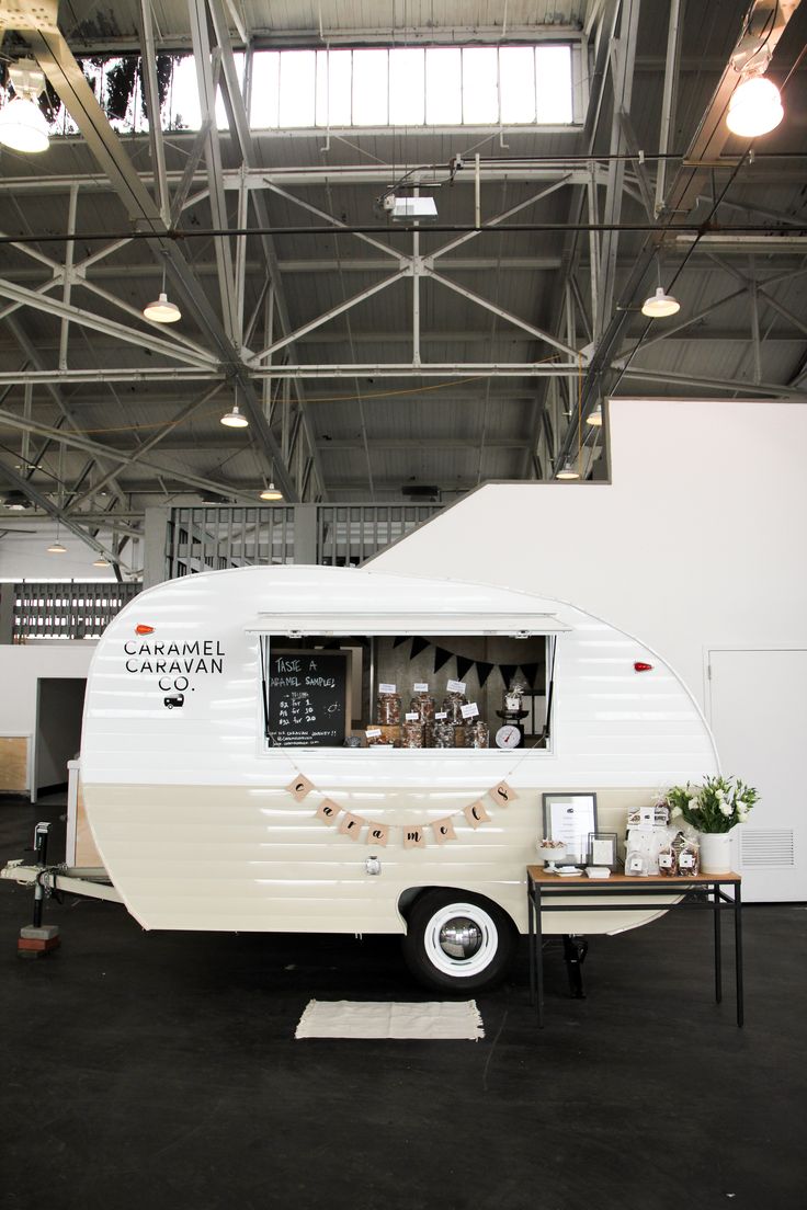 an old camper parked in a building with lights on the ceiling and windows above it