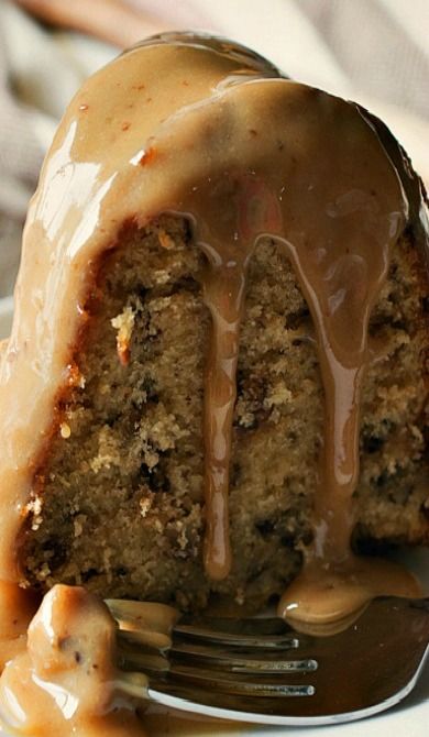 a close up of a piece of cake on a plate with a fork and caramel drizzle