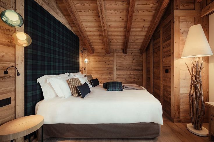 a bed in a bedroom with wooden walls and flooring next to a night stand