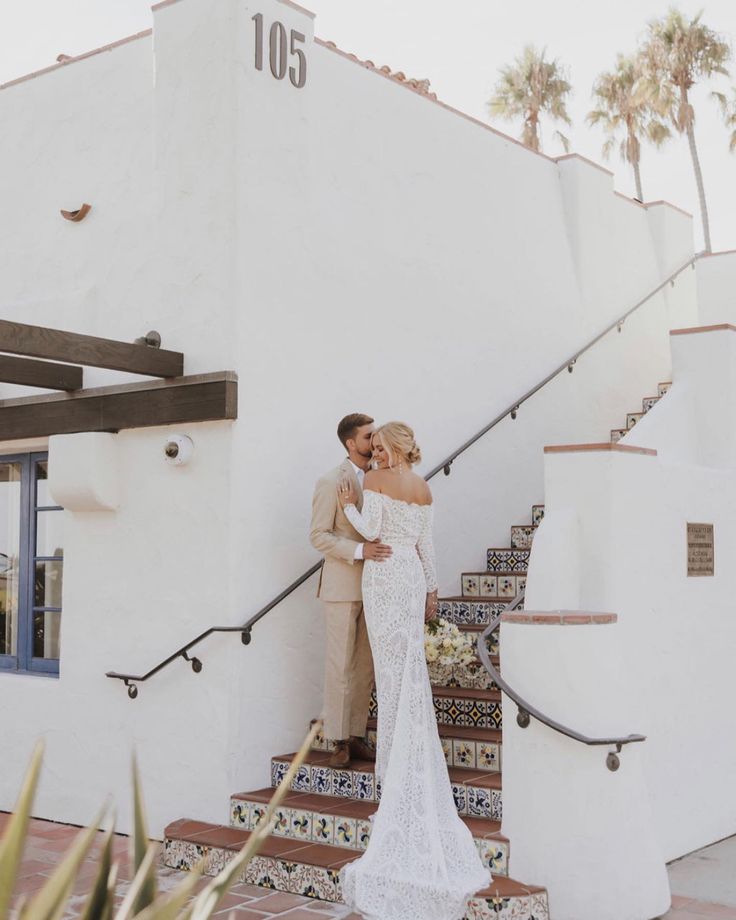 a bride and groom standing on the stairs at their wedding reception in front of a white building