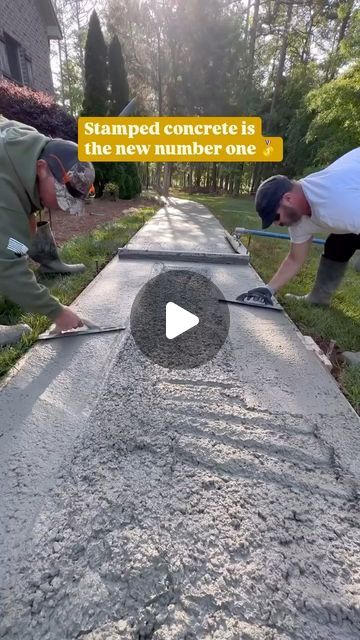 two men are working on a concrete slab in front of a house with the words stamped concrete is the new number one