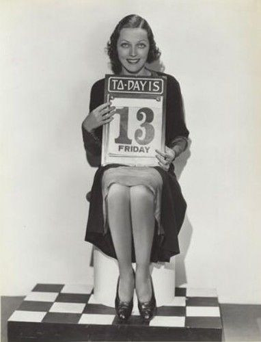 a woman sitting on top of a chair holding up a sign that says it's friday