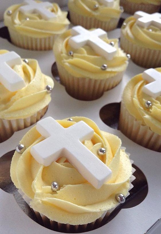 cupcakes with yellow frosting and white icing decorated to look like a cross