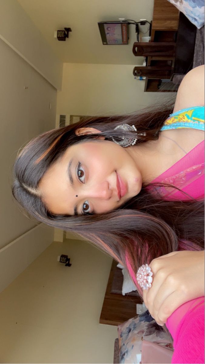 a young woman with long hair wearing a pink top is posing for the camera in her bedroom