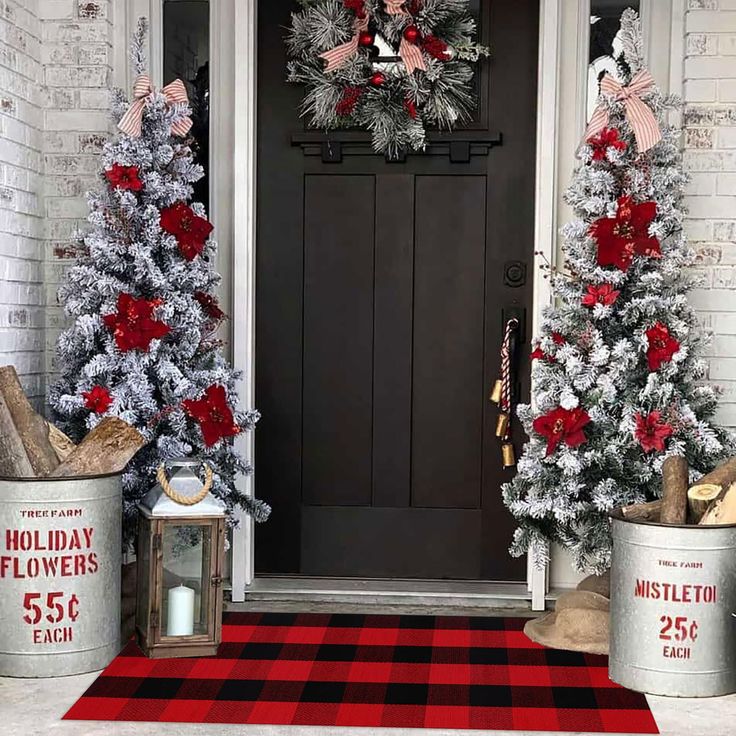 two christmas trees are decorated with red and silver tinsels in front of a black door