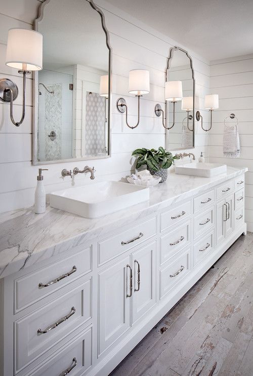 a white bathroom with double sinks and large mirrors on the wall next to each other