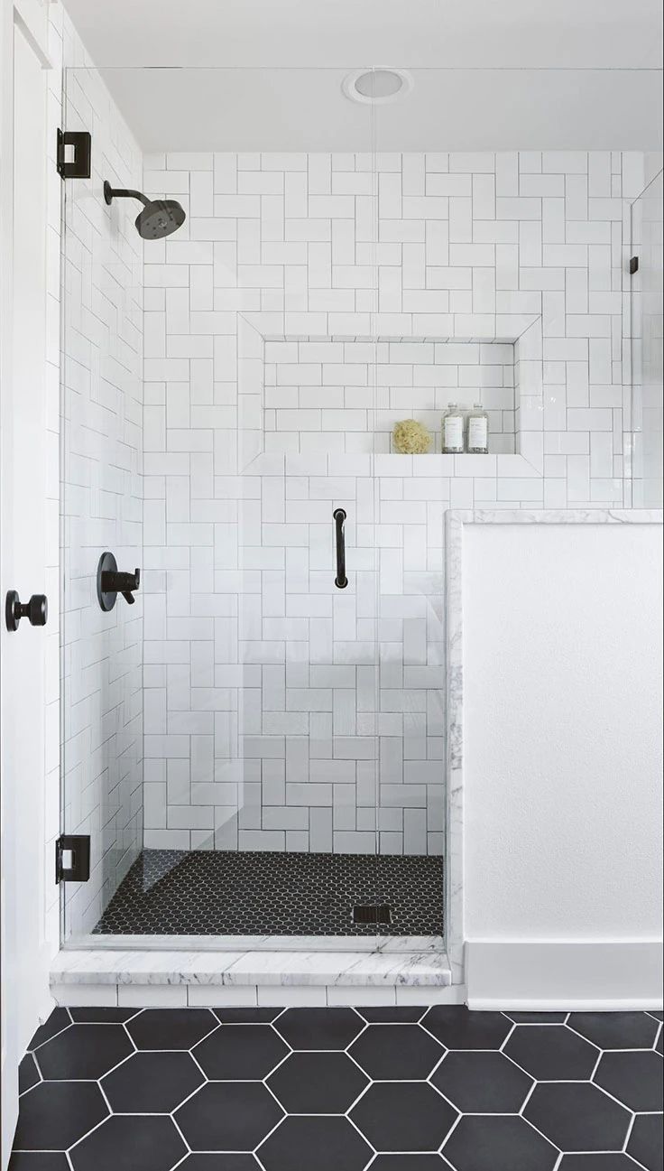 a black and white bathroom with hexagonal tiles on the floor, an open shower door