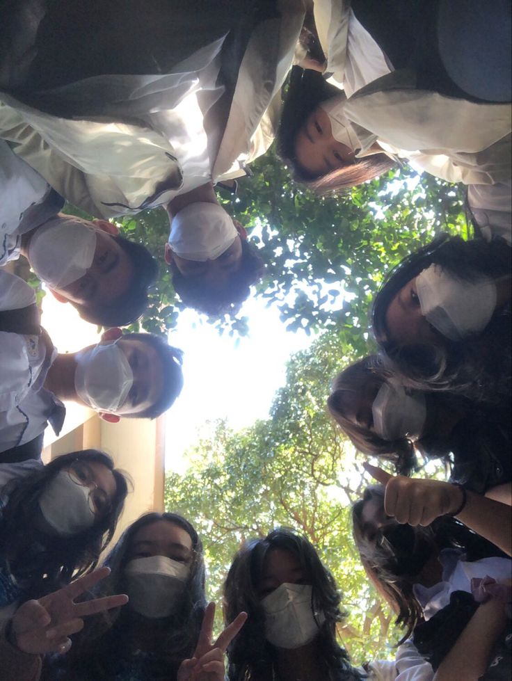 a group of people wearing masks standing in a circle