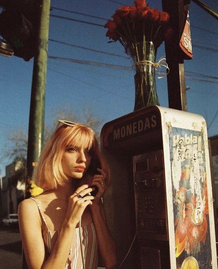 a woman talking on her cell phone next to a vending machine with roses in it