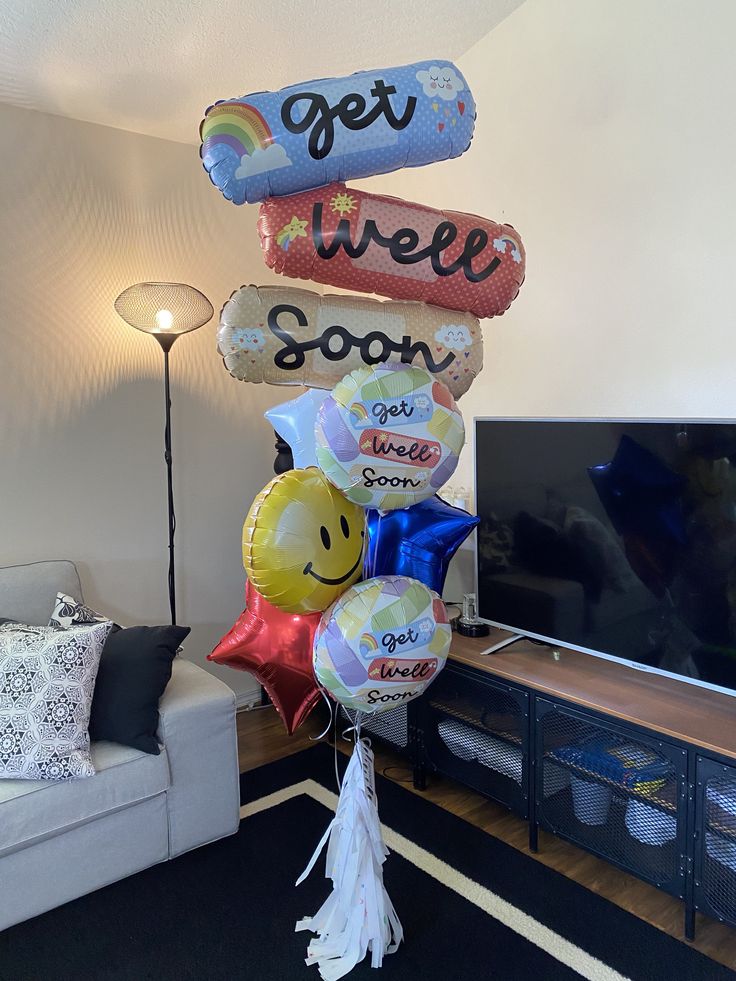 balloons are arranged in the shape of smiley face and rainbows, saying get well soon