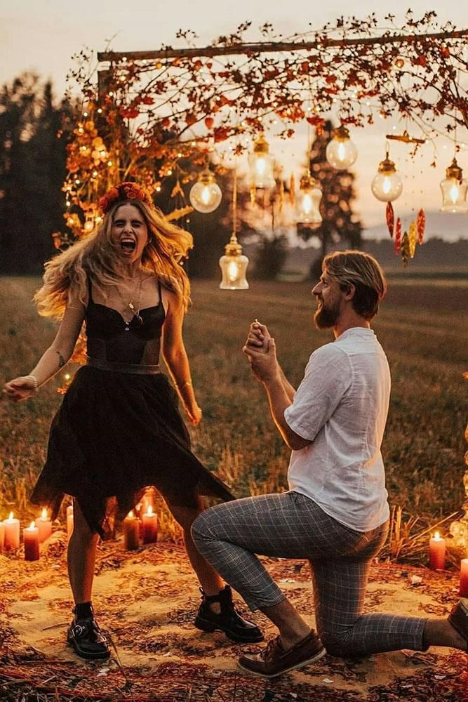 a man kneeling down next to a woman in front of an arch with candles on it