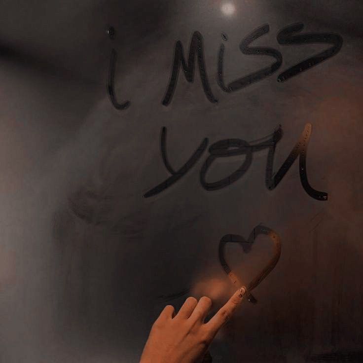 a hand writing miss you on a blackboard