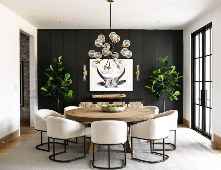 an elegant dining room with black walls and white chairs around a round wooden table surrounded by potted plants