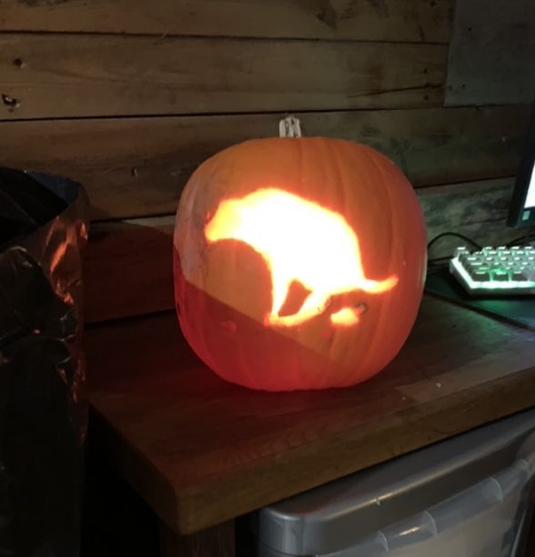 a carved pumpkin sitting on top of a wooden table next to a keyboard and mouse