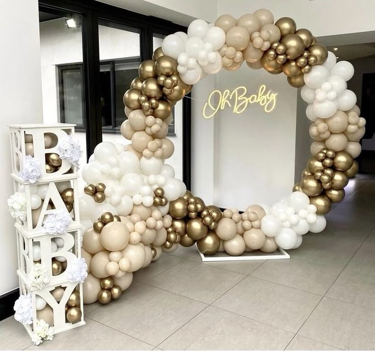 a balloon arch is decorated with gold and white balloons