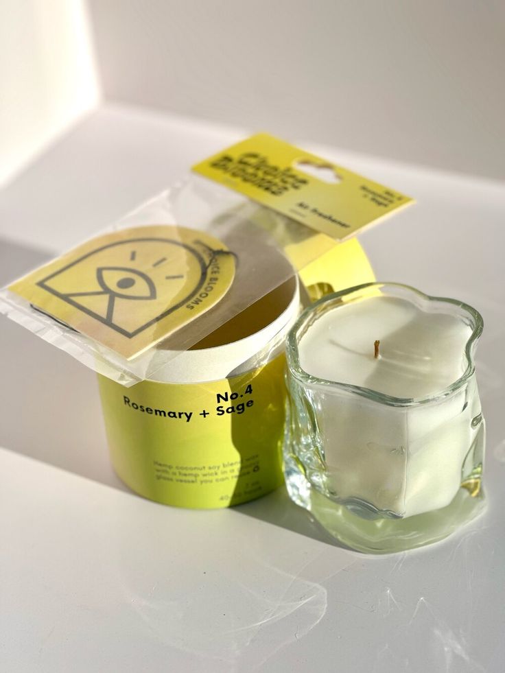 an empty glass cup next to a packaged candle