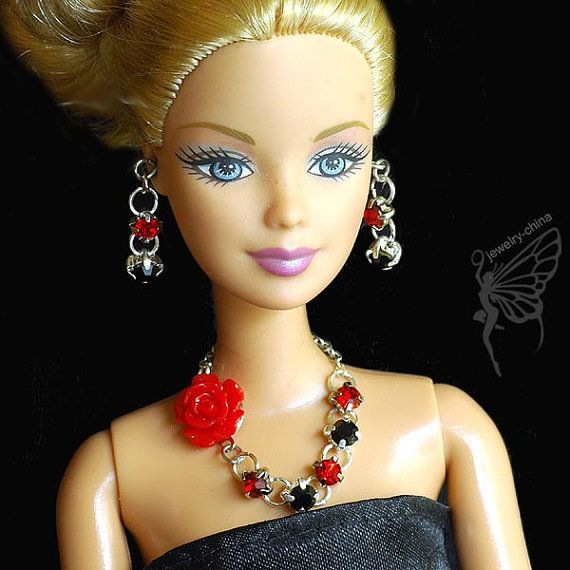 a barbie doll wearing a black dress with red flowers on it's necklace and earrings