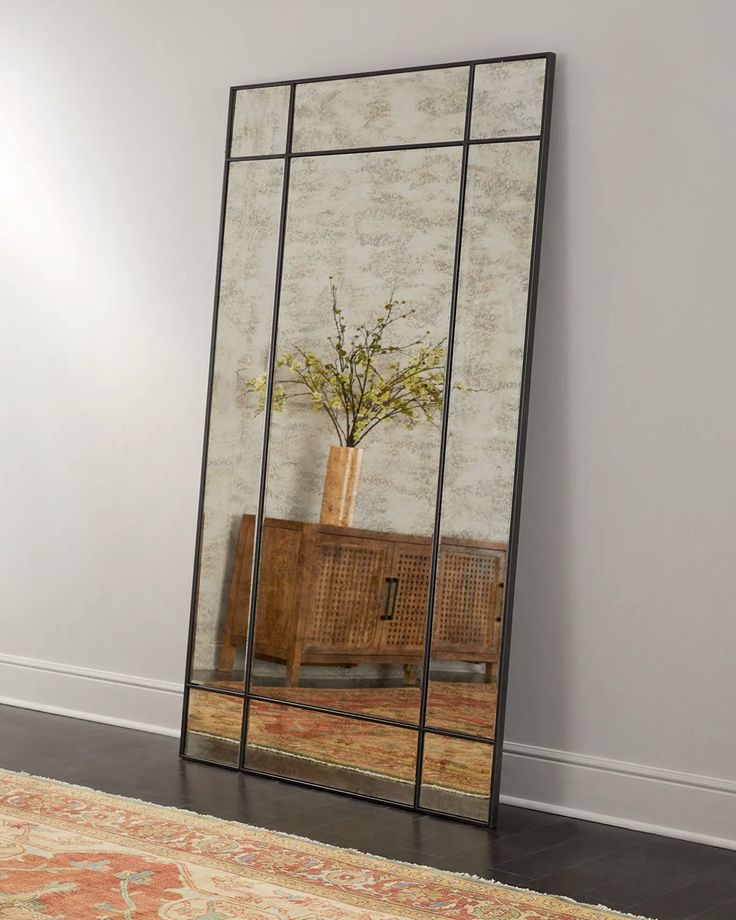 a large mirror sitting on top of a wooden floor next to a dresser and rug