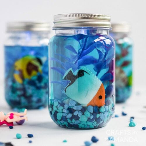 there is a fish in the jar on the table next to other items and confetti