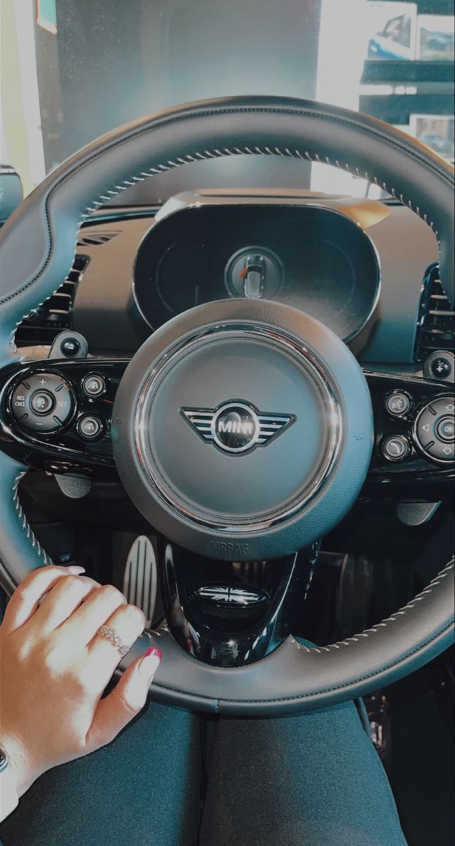 a woman driving a car with her hand on the steering wheel