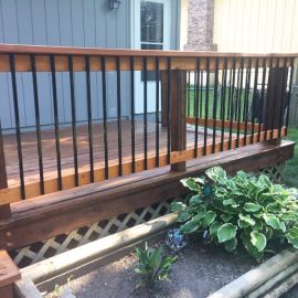 a wooden deck with railing and planters in the foreground on a home's front yard