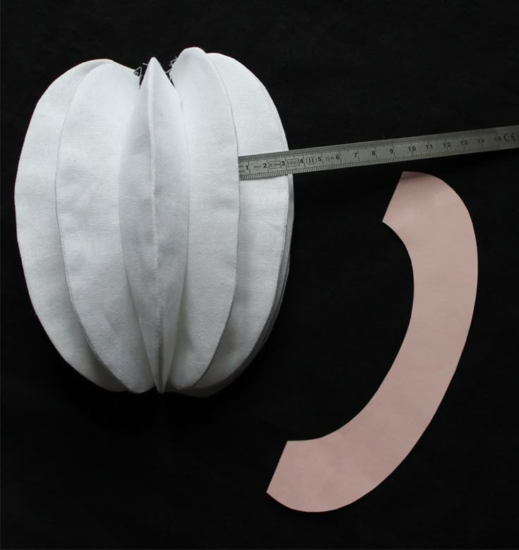 a tape measure is being used to make a paper pumpkin decoration with white ribbon on black background