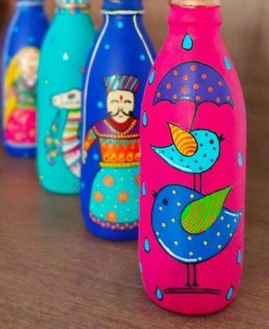 colorful painted bottles sitting on top of a wooden table next to another bottle with an image of a bird