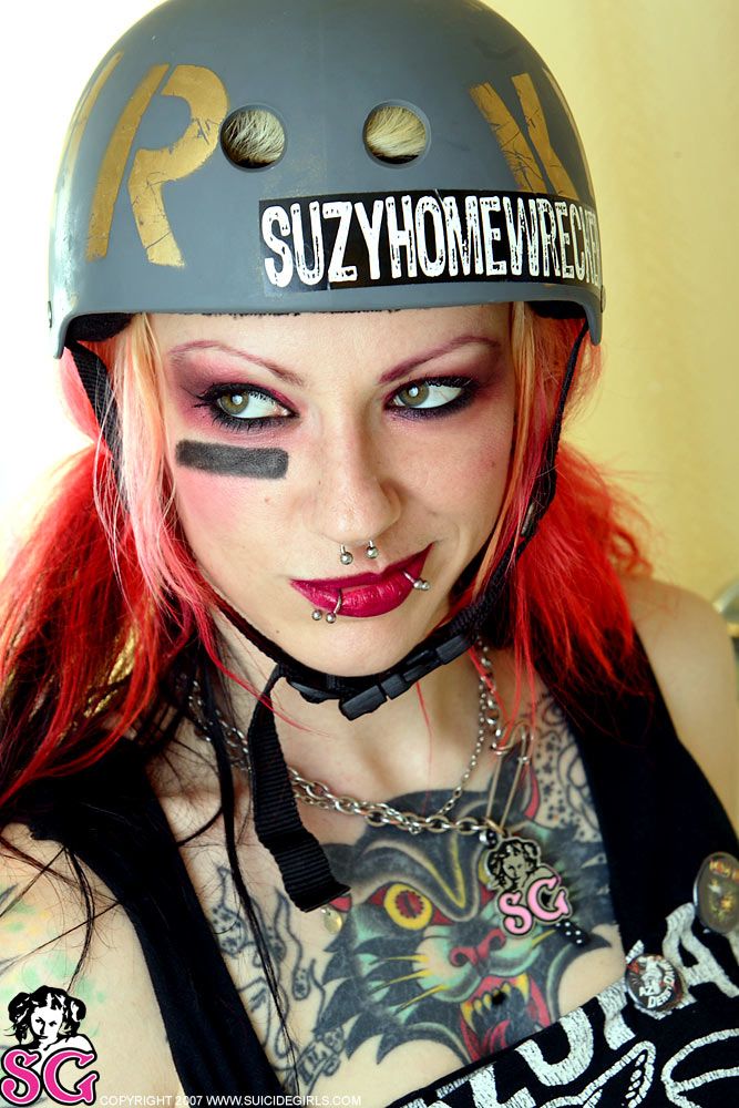 a woman with red hair wearing a black helmet and tattoos on her face is posing for the camera