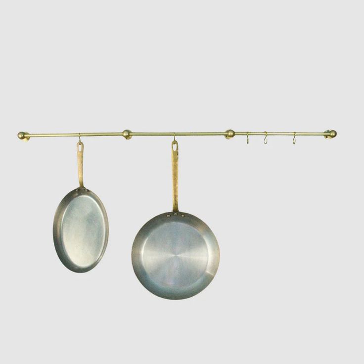 two silver pans hanging from a metal bar