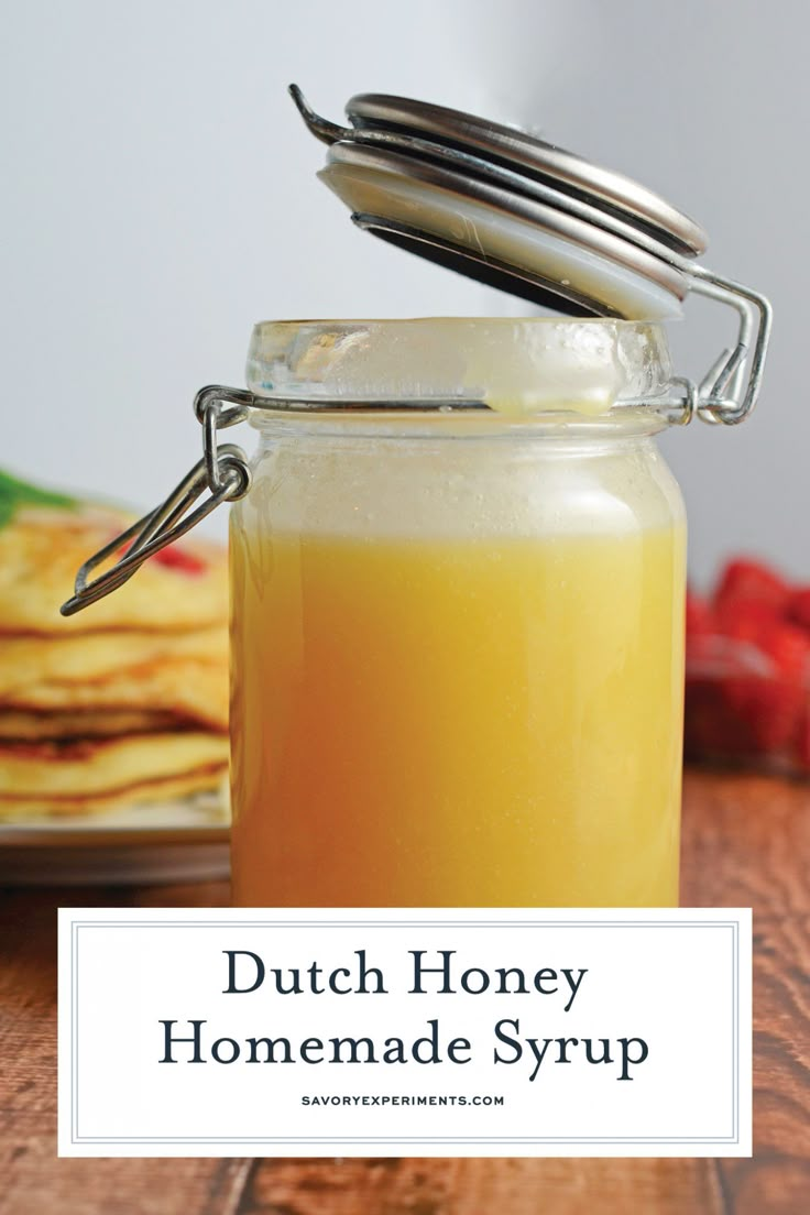 a jar filled with liquid sitting on top of a wooden table next to some pancakes