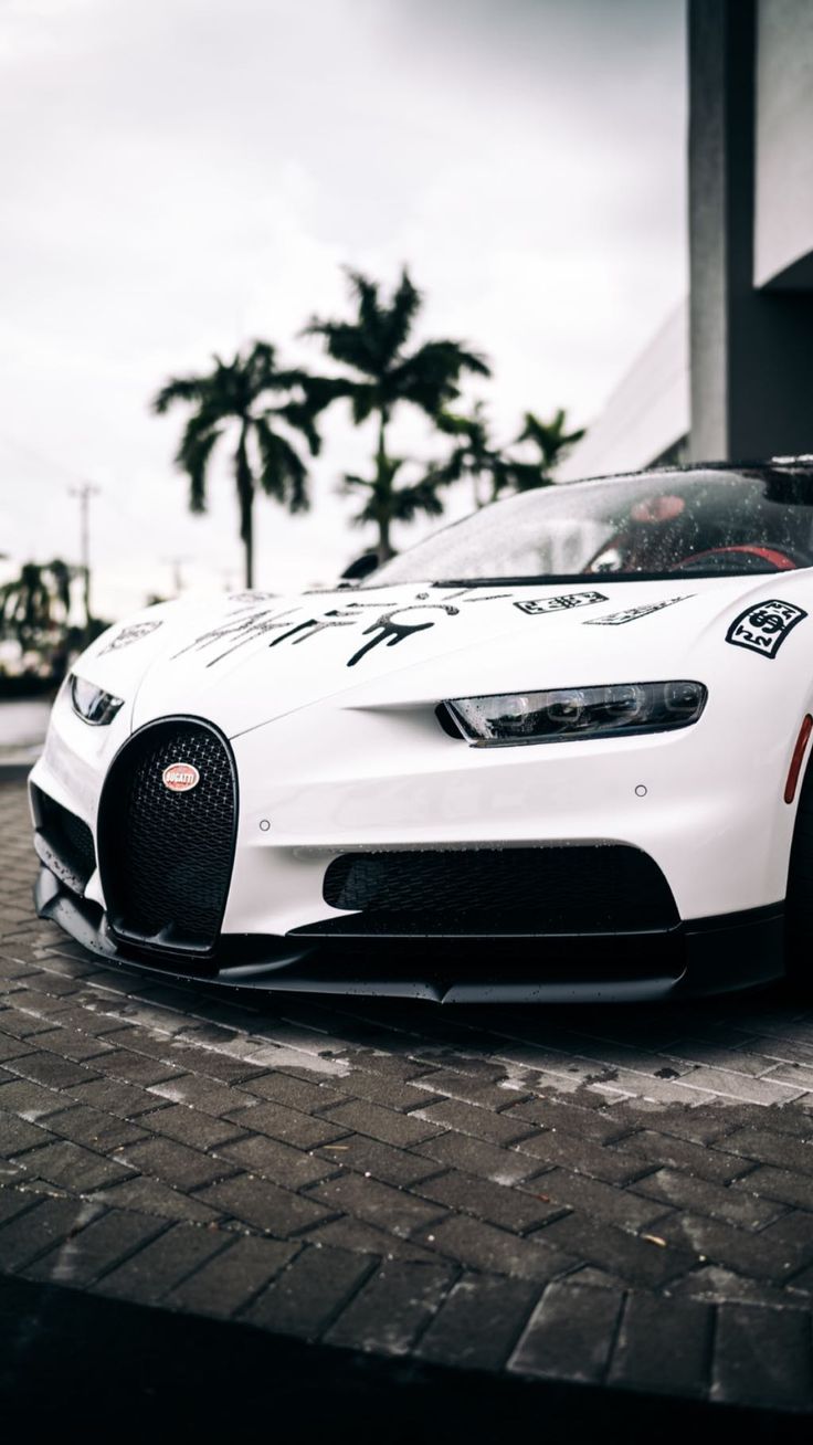 a white sports car parked in front of a building with palm trees on the side