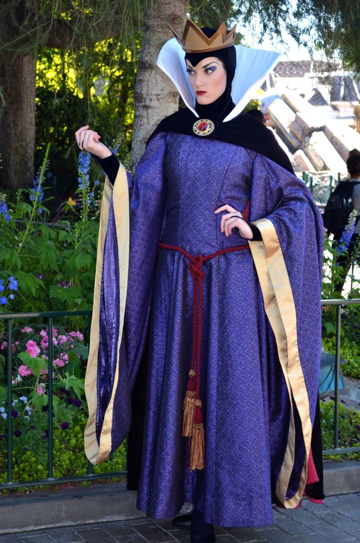 a woman dressed as evil queen standing in front of a tree