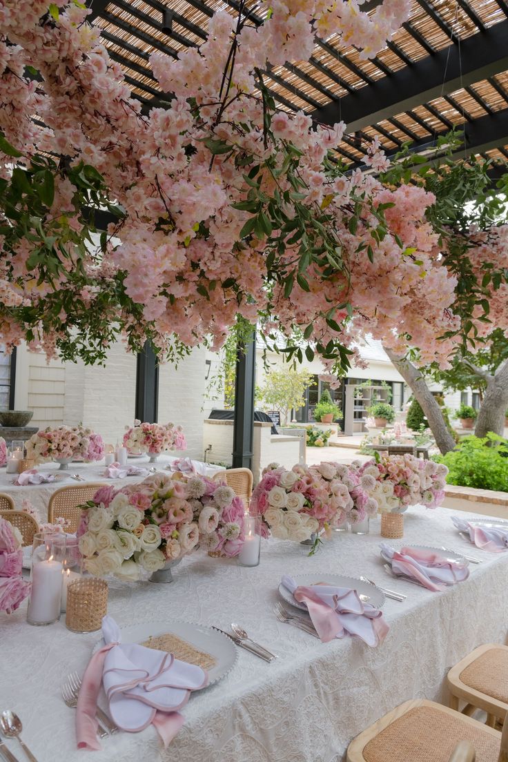 the table is set with pink flowers and place settings