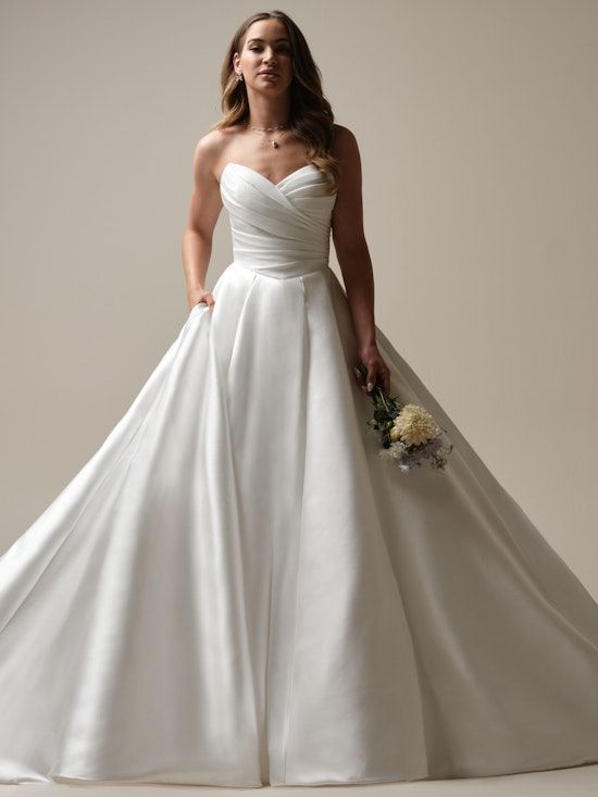 a woman in a white wedding dress posing for the camera with her hands on her hips