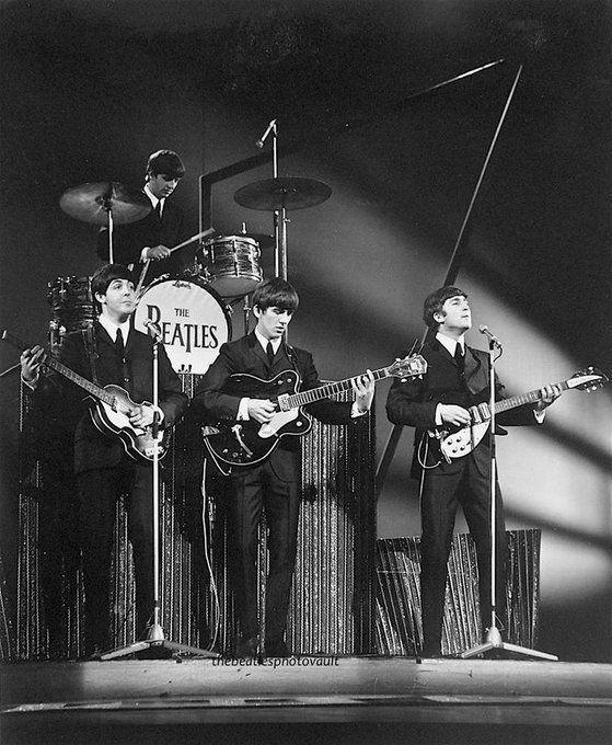 the beatles on stage with their guitars and microphones in black and white, circa