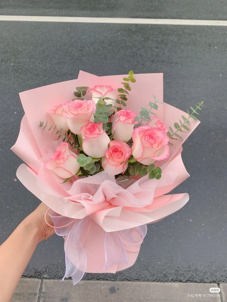 a person holding a bouquet of pink roses