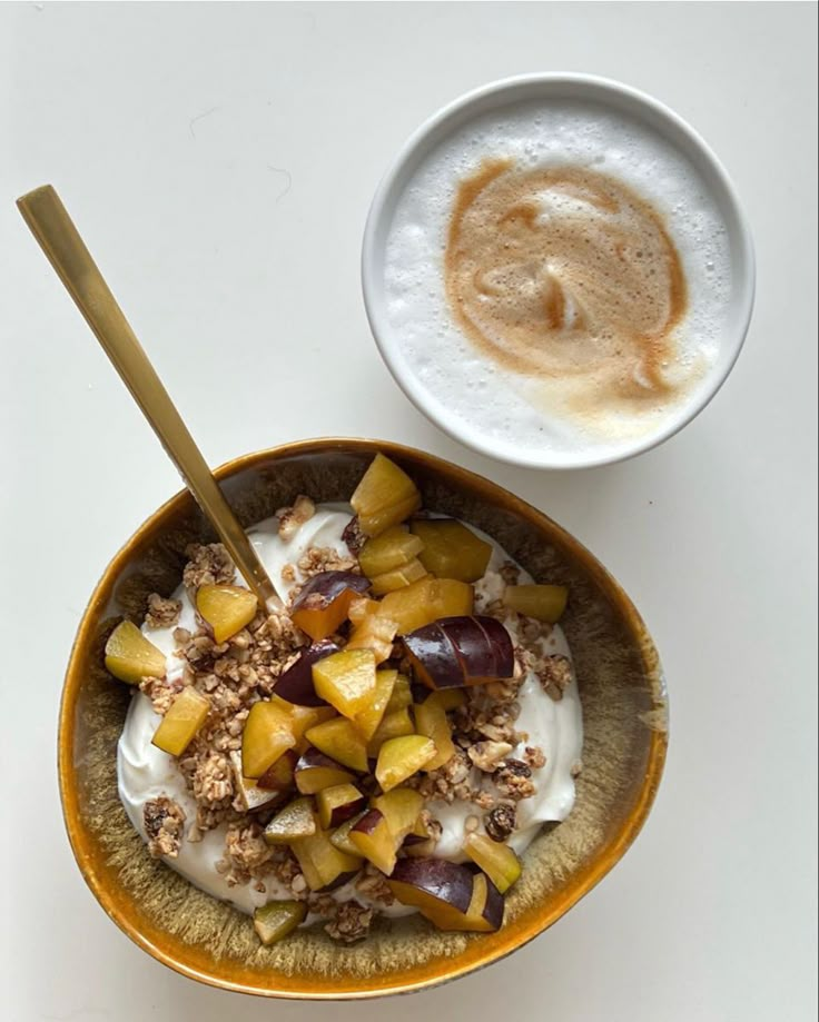 a bowl filled with fruit and yogurt next to a cup full of coffee