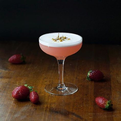 a pink cocktail with strawberries on the table