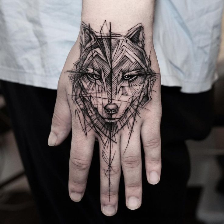 a person's hand with a tattoo on it and a wolf head in the middle