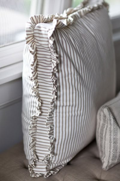 a pillow with ruffled edges sitting on a couch next to a window sill