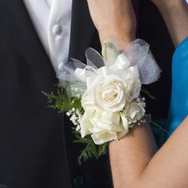 a close up of a person wearing a suit and tie with flowers on his lapel