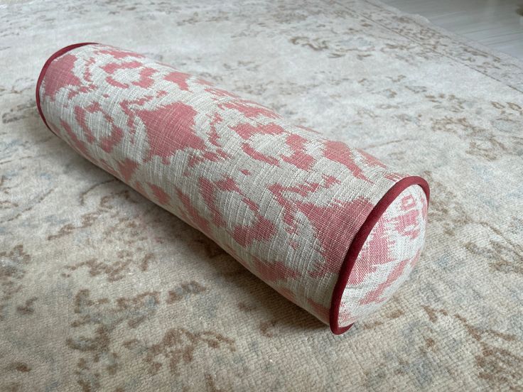 a roll of fabric sitting on top of a bed covered in pink and white patterns