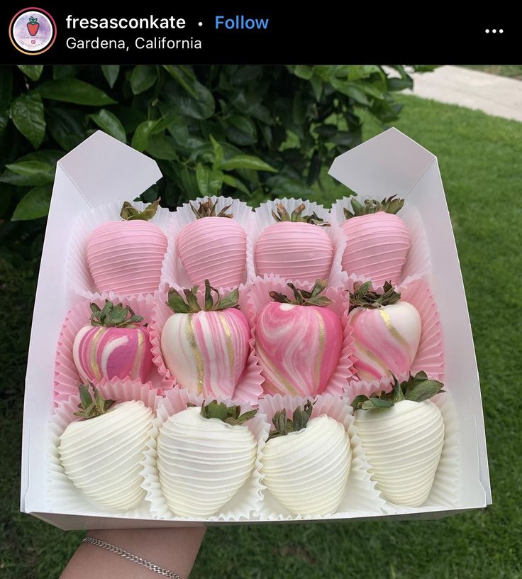 a box filled with chocolate covered strawberries in pink and white frosted wrappers