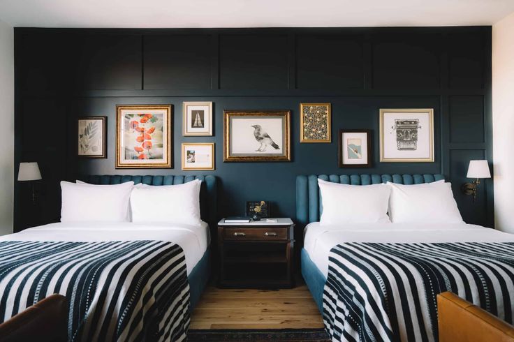 two beds in a room with black walls and pictures on the wall above them,