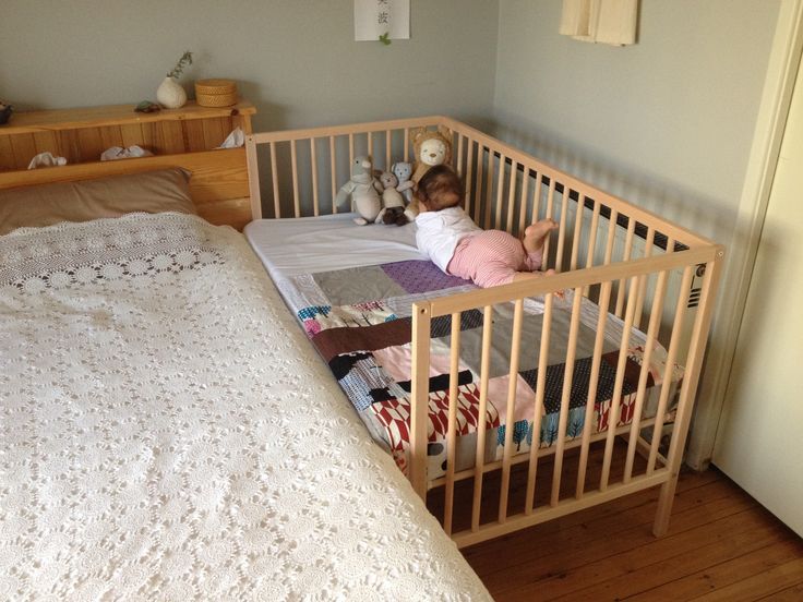 a small child laying in a crib next to a bed with stuffed animals on it