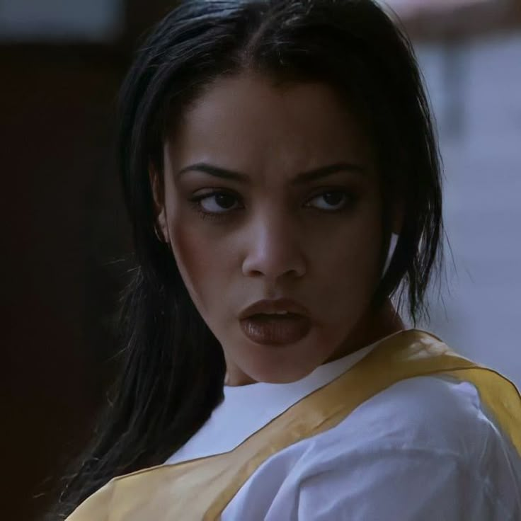 a close up of a person wearing a white shirt and yellow vest with black hair