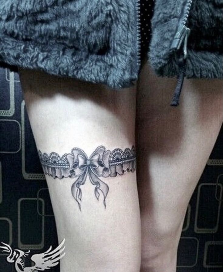 a woman's leg with a bow tattoo on it