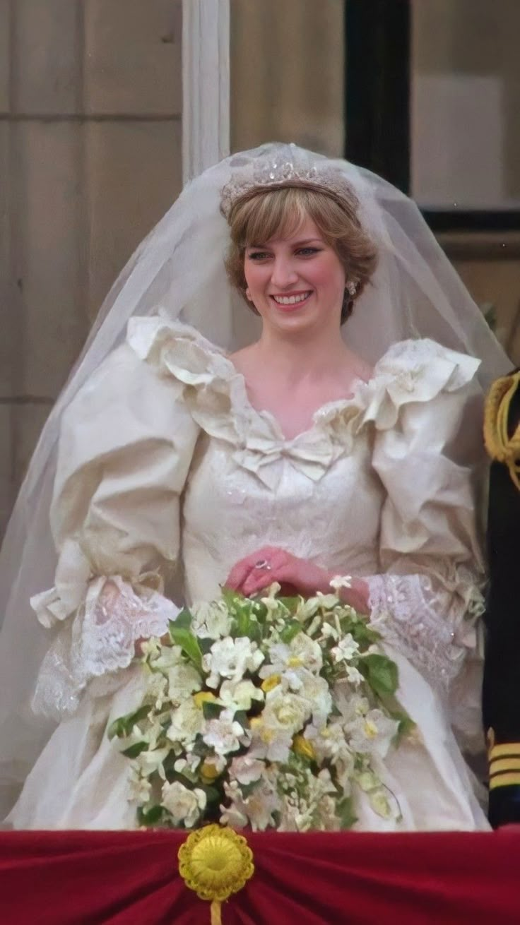 a woman in a white wedding dress holding a bouquet and standing next to a man in uniform