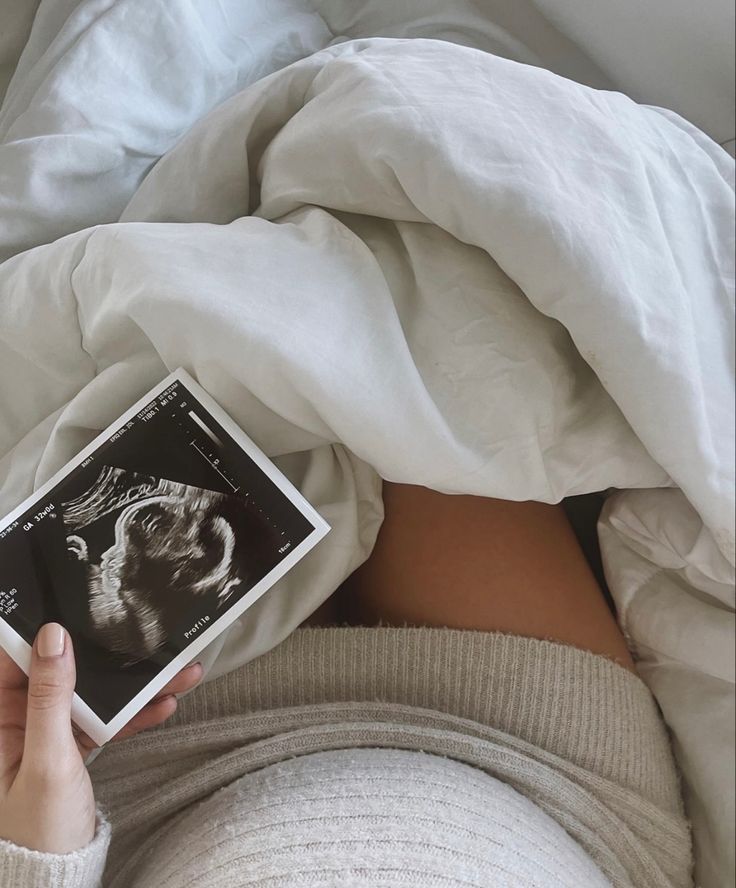 a woman is laying in bed with her stomach exposed and holding an electronic device to show the image